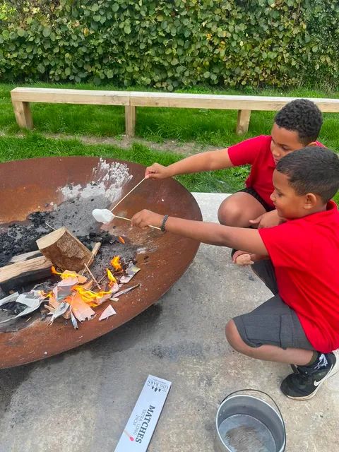 Children taking part in an outdoor fire pit cooking activity