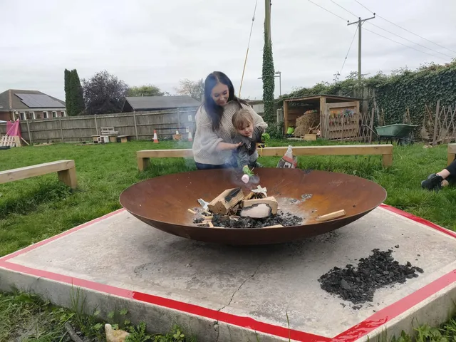 Adult and child toasting a marshmallow over the fire pit